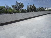 a young man riding a skateboard down a cement covered road area next to trees