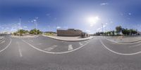 a fish eye view of a parking lot with an empty road and buildings in the background