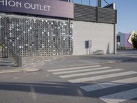 a stoplight next to the side of a building and street with a white striped crosswalk