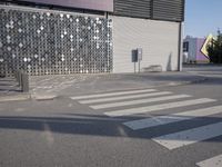 a stoplight next to the side of a building and street with a white striped crosswalk