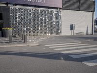 a stoplight next to the side of a building and street with a white striped crosswalk