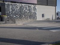 a stoplight next to the side of a building and street with a white striped crosswalk