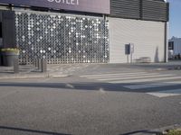 a stoplight next to the side of a building and street with a white striped crosswalk