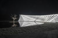 the reflection of a white, geometric object in water at night with the light reflecting on the surface