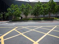 a man on the corner of an intersection in front of a building, with a pedestrian crossing the road