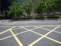 a man on the corner of an intersection in front of a building, with a pedestrian crossing the road