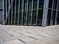 someone walking down a stone walkway in front of an office building with large windows and flooring