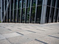 someone walking down a stone walkway in front of an office building with large windows and flooring