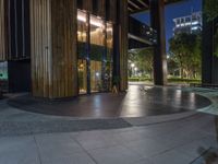 an empty walkway and entrance of a building at night with lights on it's side