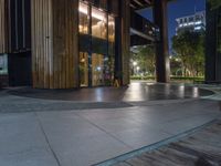 an empty walkway and entrance of a building at night with lights on it's side