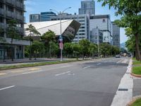 the empty road near many tall buildings is lined with trees and street signs in front of it