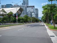 the empty road near many tall buildings is lined with trees and street signs in front of it