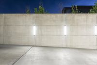 the large concrete wall has been illuminated by recessed lights at night on either side of it