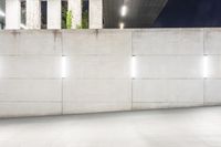 the large concrete wall has been illuminated by recessed lights at night on either side of it