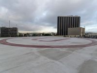 a circle sign sits in the middle of a cement plaza with buildings and cars around it