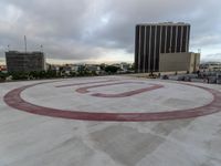 a circle sign sits in the middle of a cement plaza with buildings and cars around it