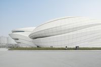 a person on a bicycle in front of an enormous building with lots of windows and curved shapes