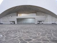 a building is constructed into an archway shape and features a stone floor and a circular walkway