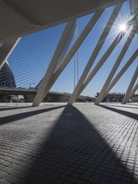the shadow of the bridge is cast across the cement pavement that has been set out in the shape of a pyramid