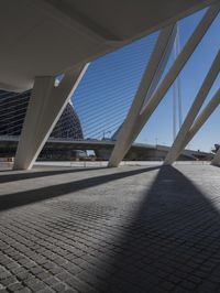 the shadow of the bridge is cast across the cement pavement that has been set out in the shape of a pyramid