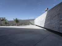 a building with concrete walls and a big parking lot under a blue sky with white clouds