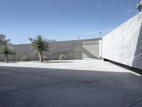 a building with concrete walls and a big parking lot under a blue sky with white clouds