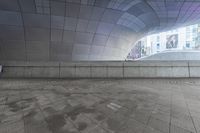 the man is walking in an urban space with his skateboard to his side and looking up