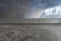 the man is walking in an urban space with his skateboard to his side and looking up