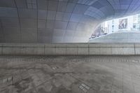 the man is walking in an urban space with his skateboard to his side and looking up