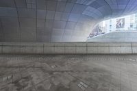 the man is walking in an urban space with his skateboard to his side and looking up