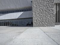 a tall building with some big windows by itself that is on concrete and has lots of cement