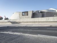 there is a very large cement structure with white accents on it by the street and a curb with a bus in it