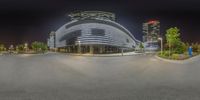 a futuristic looking building at night in the city by itself - - - - -