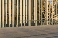 an empty street that is next to a building with glass walls and a man walking down the sidewalk