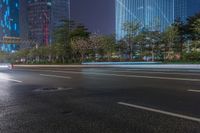 a city street with buildings and neon lights at night time in hong china as seen from an empty city highway