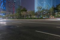 a city street with buildings and neon lights at night time in hong china as seen from an empty city highway