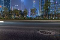 a city street with buildings and neon lights at night time in hong china as seen from an empty city highway