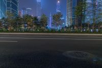 a city street with buildings and neon lights at night time in hong china as seen from an empty city highway