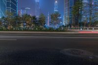 a city street with buildings and neon lights at night time in hong china as seen from an empty city highway