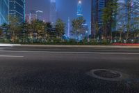 a city street with buildings and neon lights at night time in hong china as seen from an empty city highway