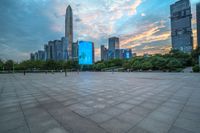 a city skyline is shown from the ground at sunset, and a person walks on the pavement