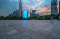 a city skyline is shown from the ground at sunset, and a person walks on the pavement