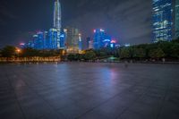 city skyline in the distance with square paving with lights on the ground in the foreground