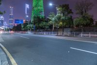 a city street with buildings and neon lights at night time in hong china as seen from an empty city highway