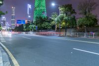 a city street with buildings and neon lights at night time in hong china as seen from an empty city highway