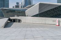 a boy riding his skateboard in front of the building that has a silver exterior