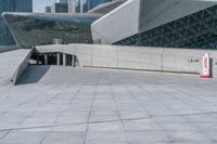 a boy riding his skateboard in front of the building that has a silver exterior