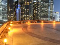 two park benches are on a roof overlooking cityscape at night time time with buildings in the background