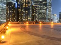 two park benches are on a roof overlooking cityscape at night time time with buildings in the background