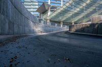 an empty street in front of a stadium with curved roof and concrete walls with stairs